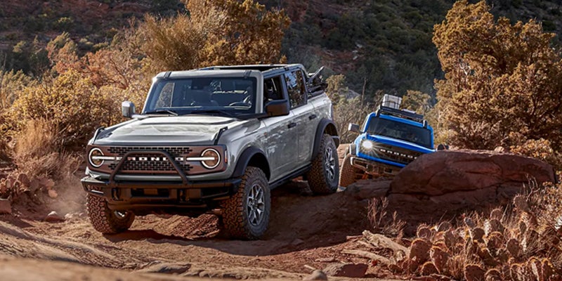 Two 2023 Ford Broncos traversing rugged terrain