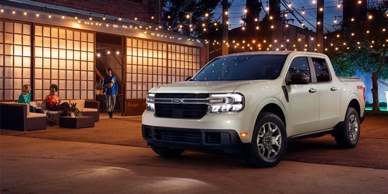 A white 2024 Ford Maverick parked outside a dimly lit