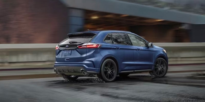 A blue 2024 Ford Edge driving through a city