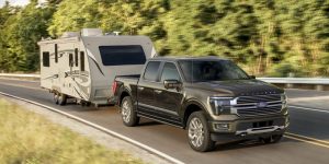 The 2025 Ford F-150 hauling a camper trailer down the highway.