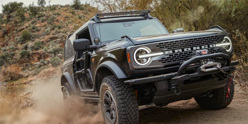 Black 2024 Ford Bronco powering uphill on a dirt road
